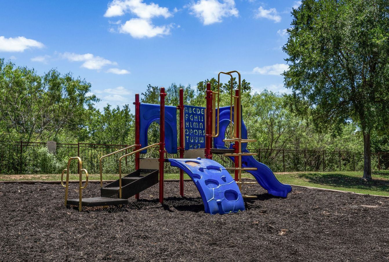 Colorful playground with slides and climbing features in a wooded park under a blue sky