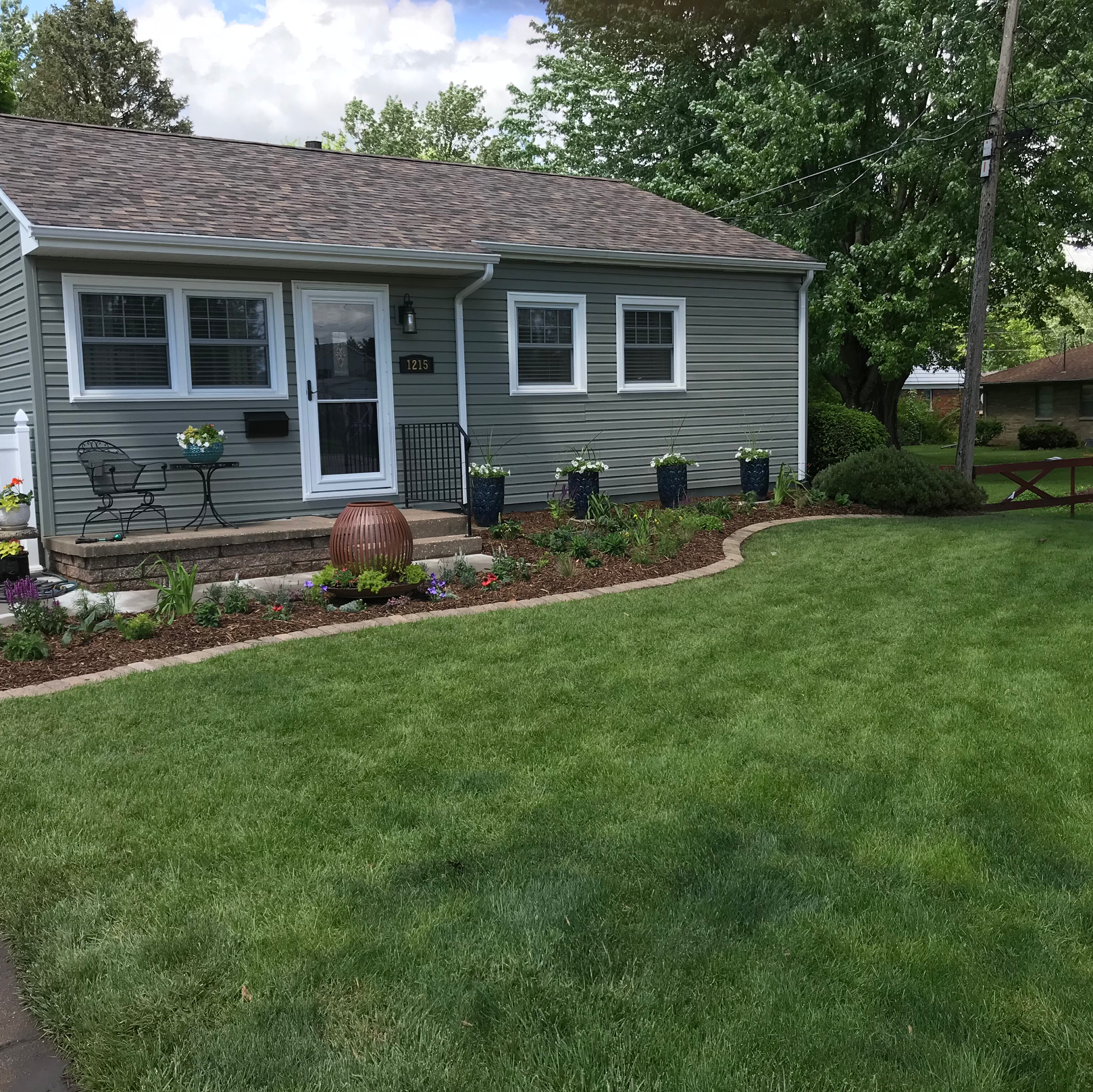 Green house with neatly manicured lawn and landscaping.
