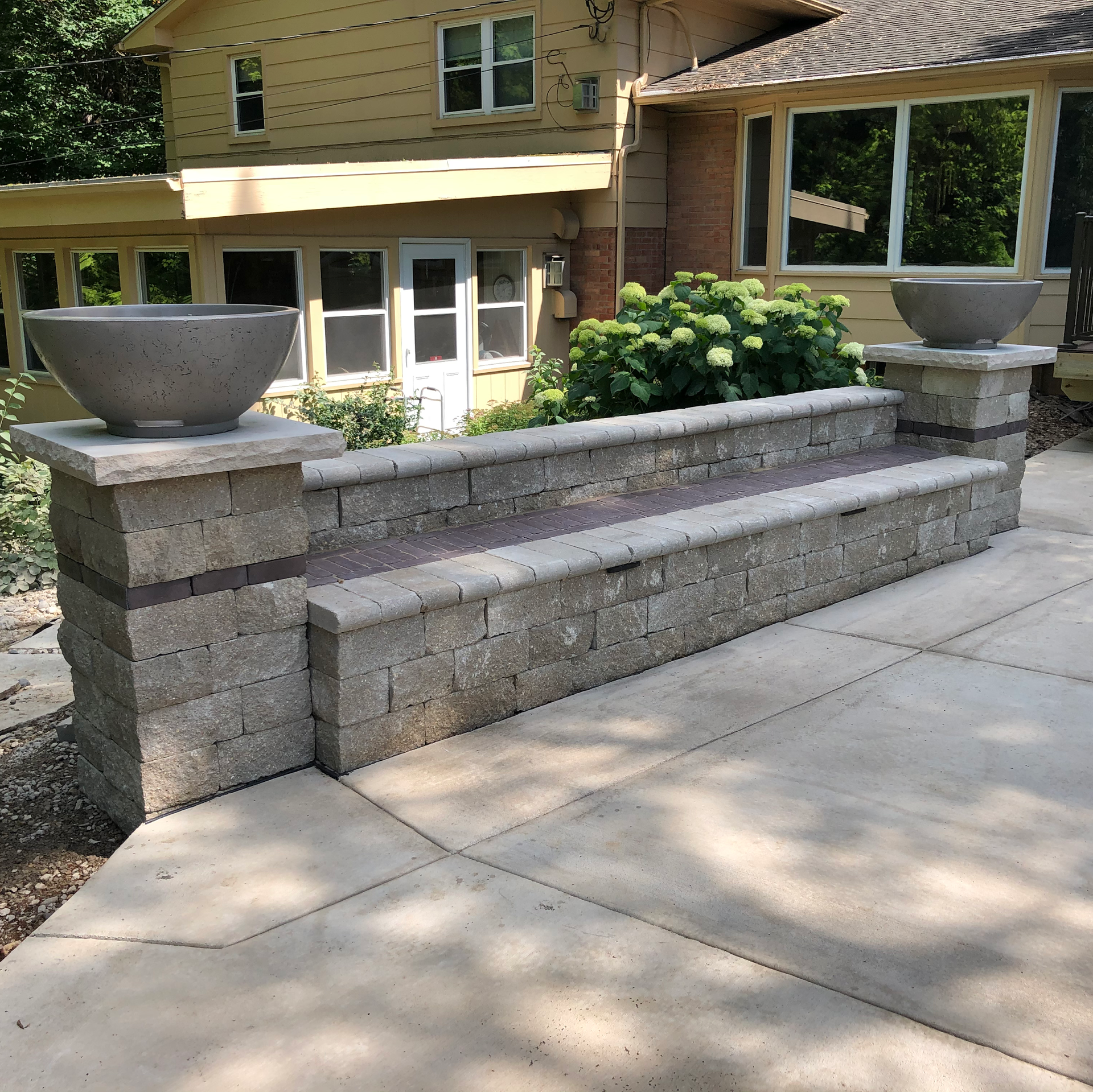 Concrete tiered patio with large planters and house in background.