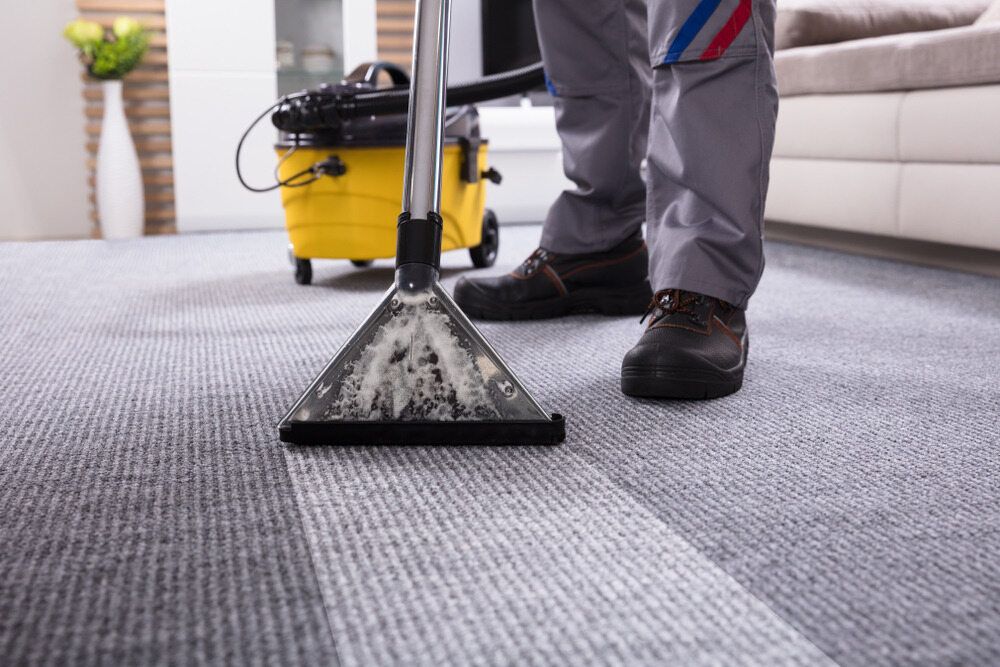 A Person is Cleaning a Carpet With a Vacuum Cleaner — South Pacific Cleaning in Bentley Park, QLD