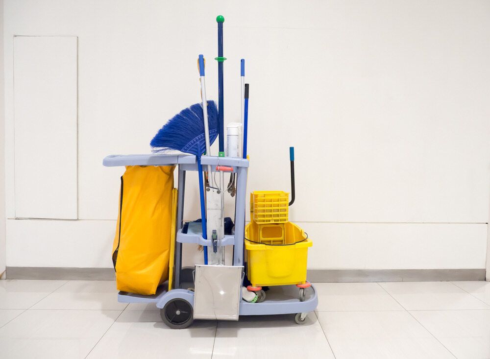 A Cleaning Cart With a Mop, Broom, and Bucket on a Tiled Floor — South Pacific Cleaning in Bentley Park, QLD