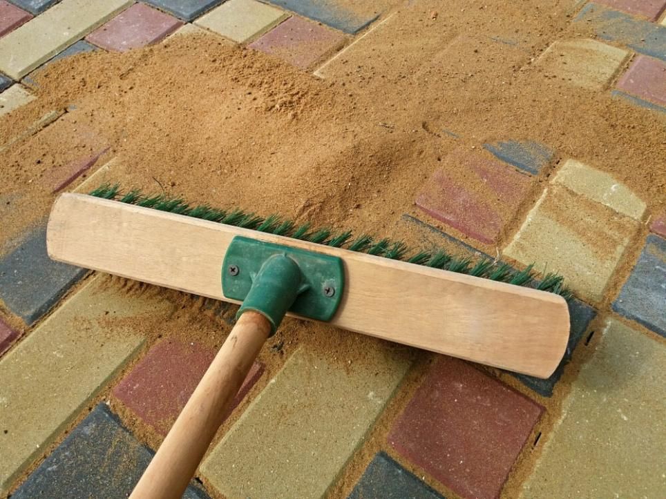 A Broom With a Green Handle is Laying on a Brick Floor — South Pacific Cleaning in Bentley Park, QLD