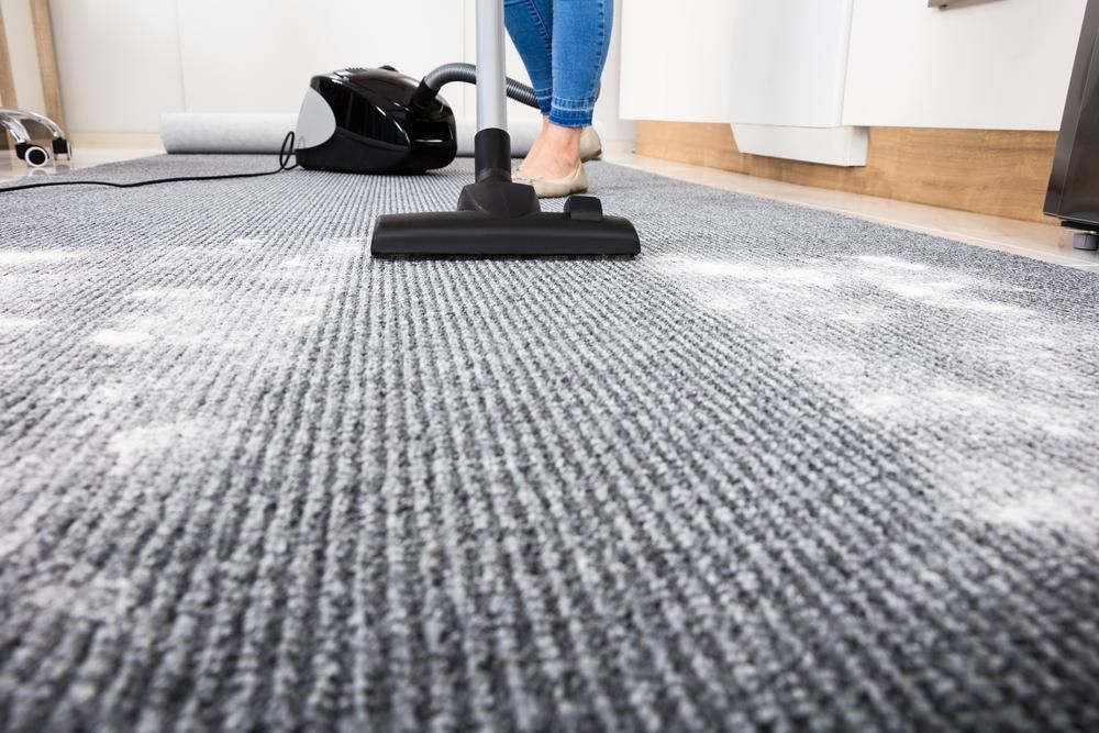 A Woman is Using a Vacuum Cleaner to Clean a Carpet — South Pacific Cleaning in Bentley Park, QLD