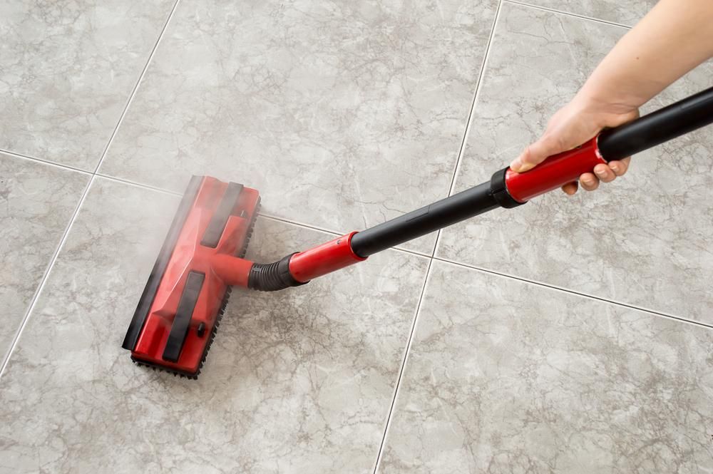A Person is Using a Vacuum Cleaner to Clean a Tile Floor — South Pacific Cleaning in Bentley Park, QLD