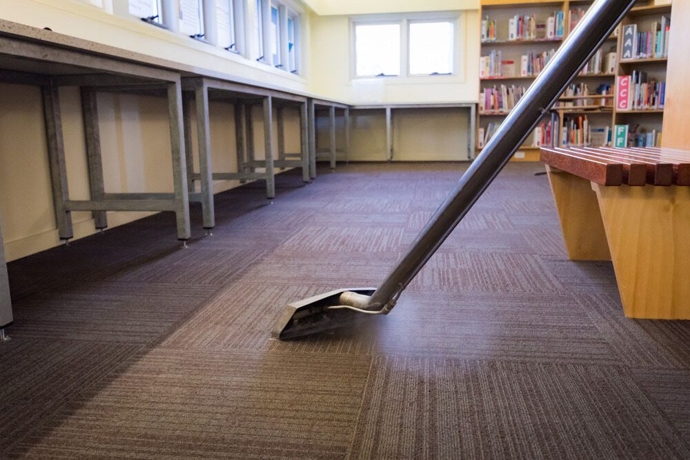 A Vacuum Cleaner is Cleaning a Carpeted Floor in a Library — South Pacific Cleaning in Edmonton, QLD