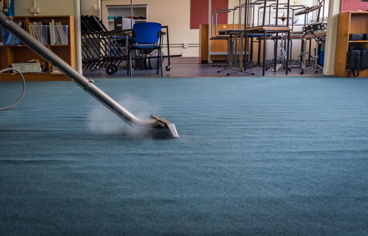 A Vacuum Cleaner is Cleaning a Blue Carpet in a Classroom — South Pacific Cleaning in Redlynch, QLD