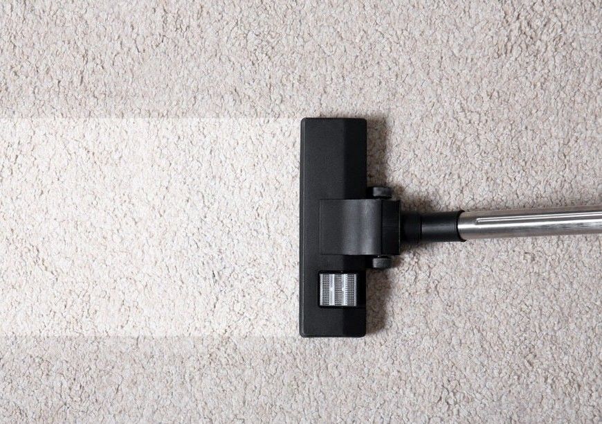 A Vacuum Cleaner is Cleaning a White Carpet — South Pacific Cleaning in Smithfield, QLD