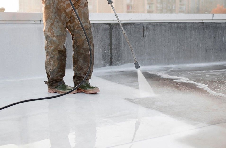 A Man is Using a High Pressure Washer to Clean a Roof — South Pacific Cleaning in Smithfield, QLD