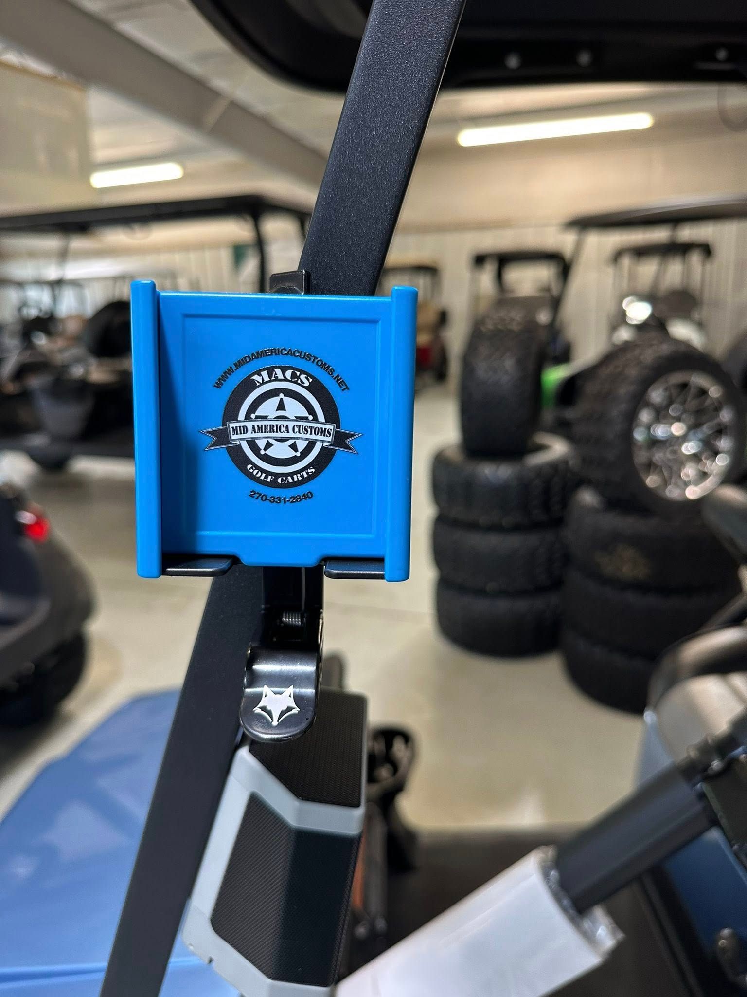 Blue golf cart accessory with logo mounted on golf cart roof support.