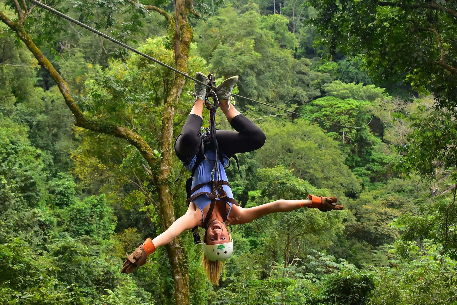 A girl is climbing a canyon and a man is under her. 