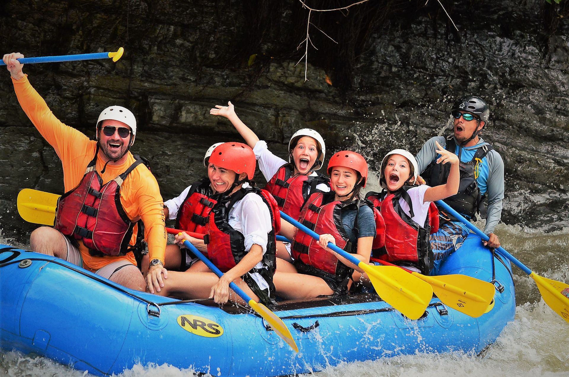 A group of people are rafting down a river in a blue raft.