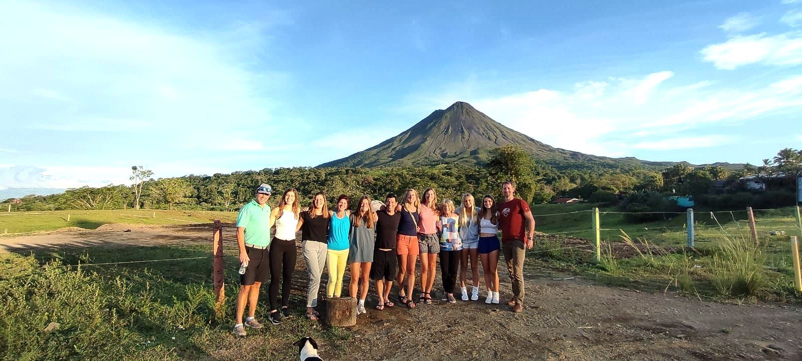 A group of people are posing for a picture in front of a mountain.