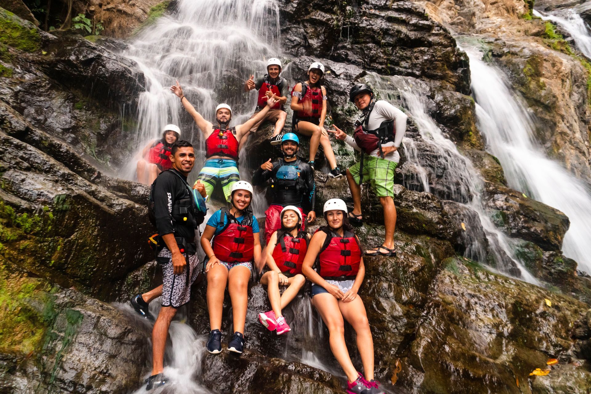 A group of people are posing for a picture in front of a waterfall.