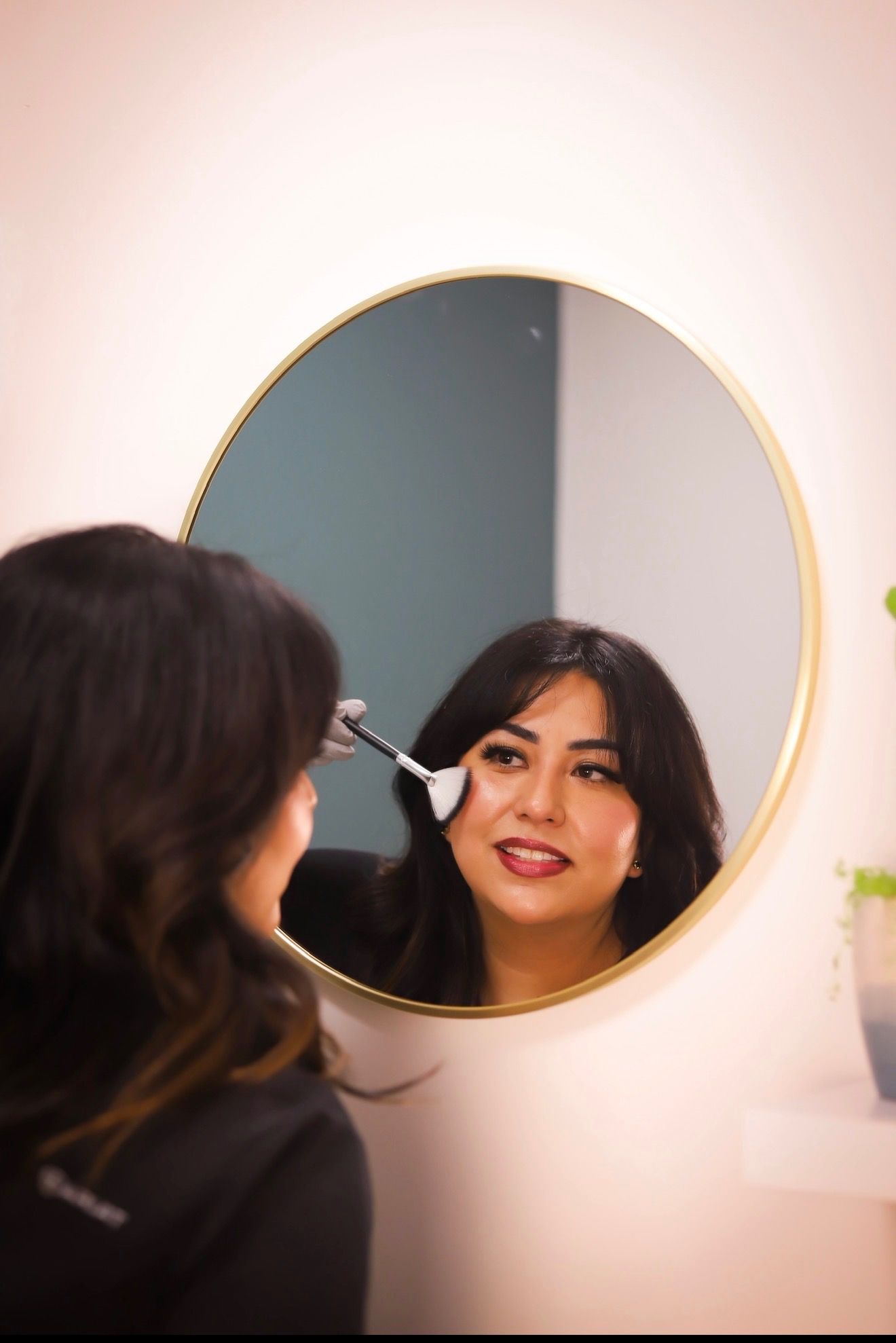 Owner applying makeup in a round mirror.
