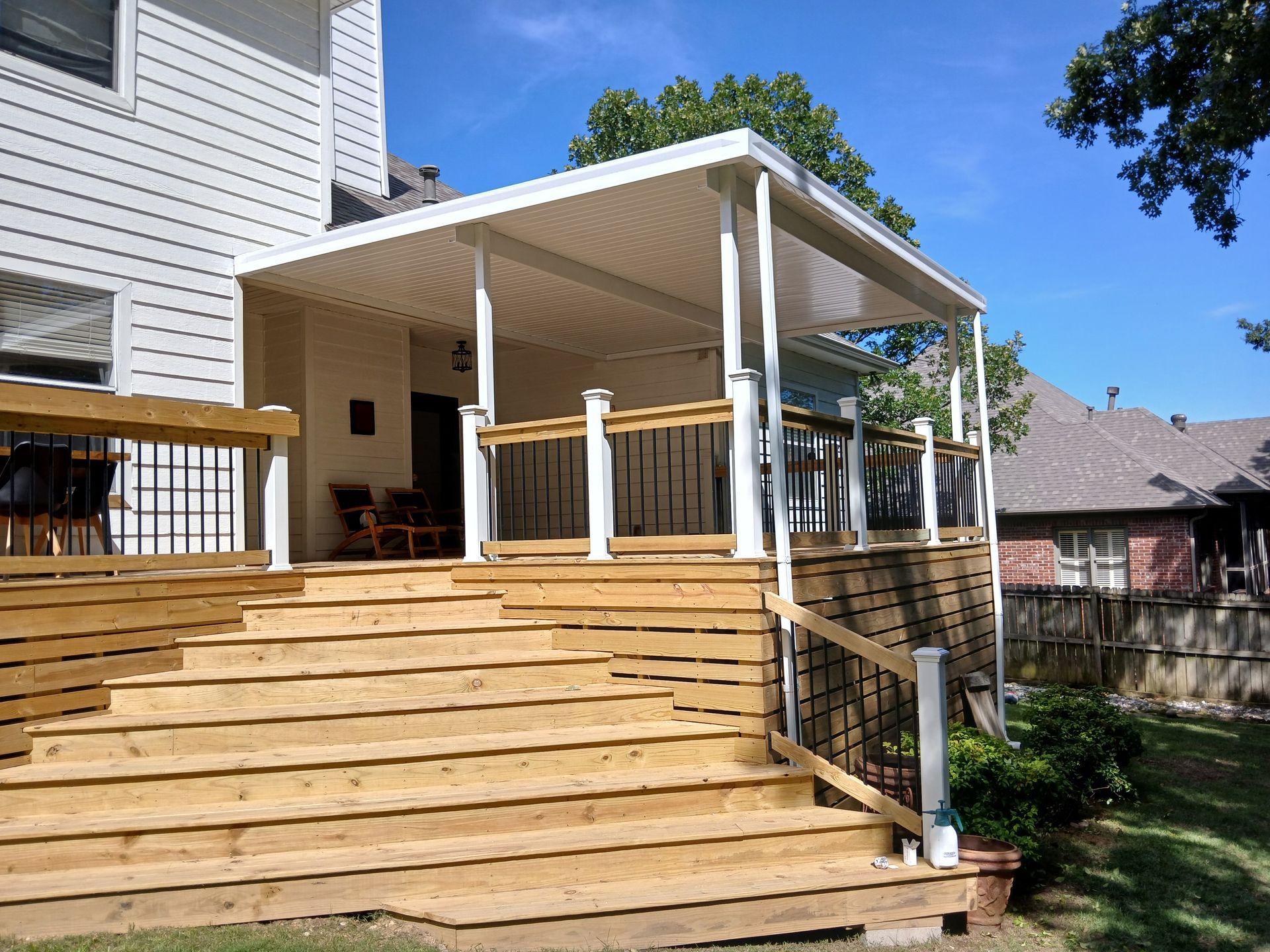 Backyard deck with wooden stairs and a covered porch attached to a house