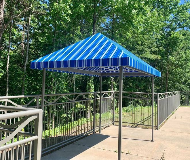 A blue and white striped canopy is sitting on top of a concrete walkway.