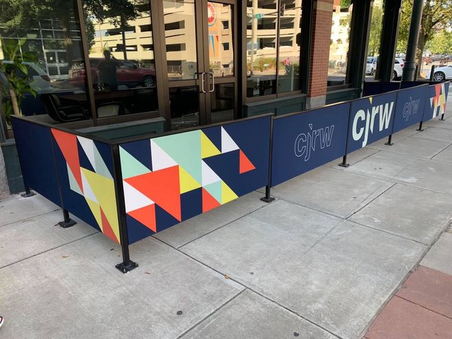 A colorful fence is sitting on the sidewalk in front of a building.