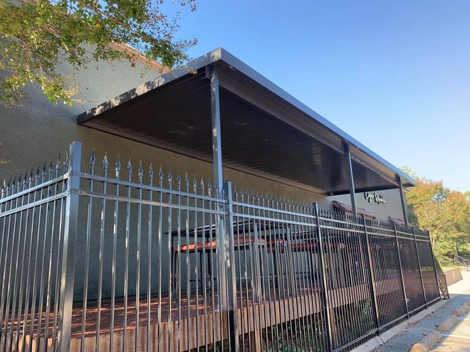 A metal fence surrounds a deck with a covered porch.