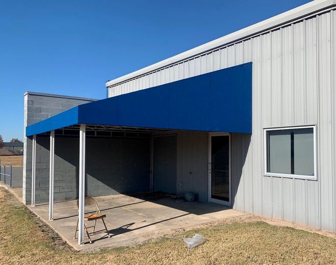 A white building with a blue awning on the side of it.