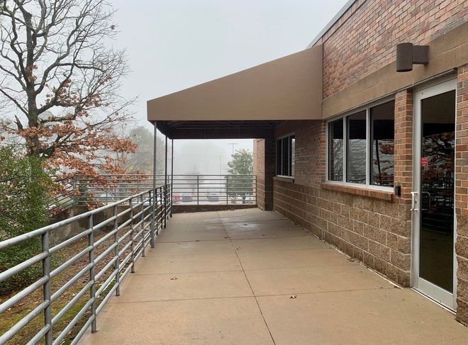 A walkway leading to a brick building with a canopy over it.