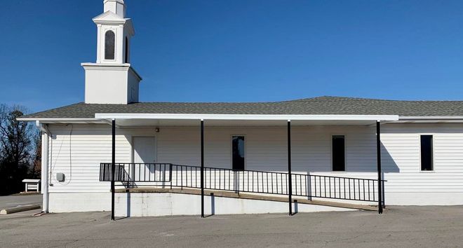A white building with a tower on top of it and a ramp leading to it.