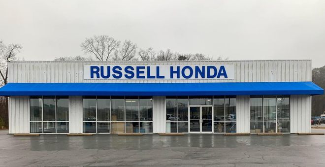 A russell honda car dealership with a blue awning on a cloudy day.
