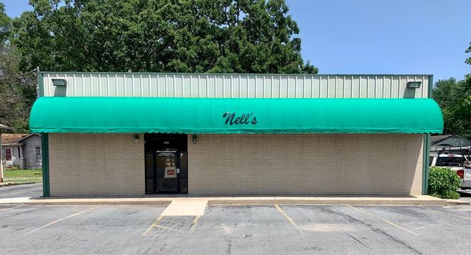 A white building with a green awning that says kell 's