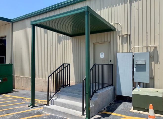 A building with a green canopy over the entrance and stairs leading up to it.