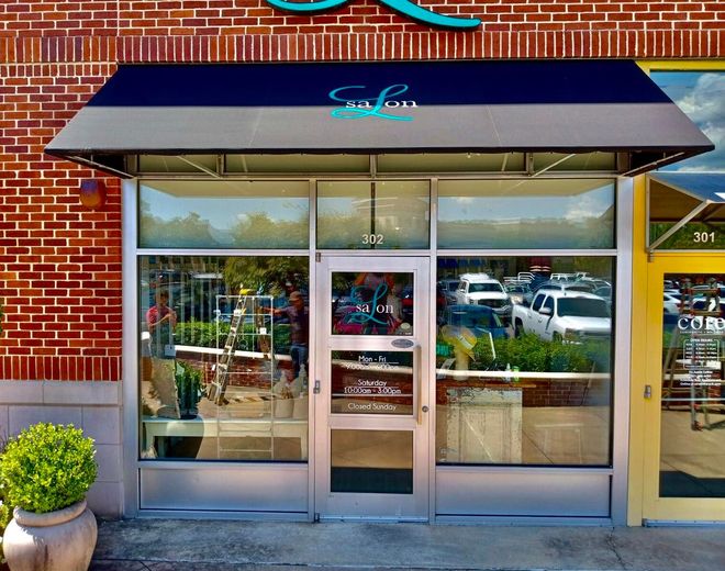 A store front with a blue awning that says salon