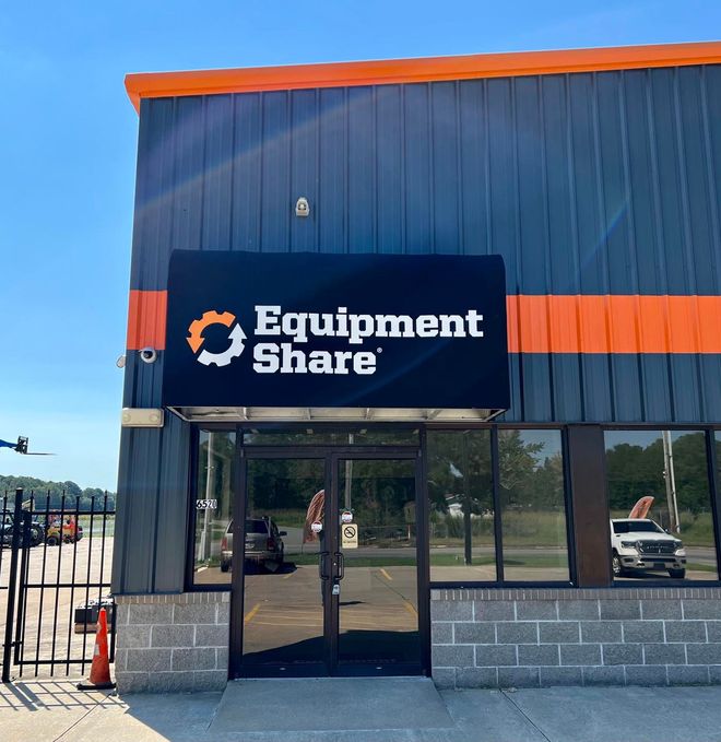 A black and orange building with a sign that says equipment share