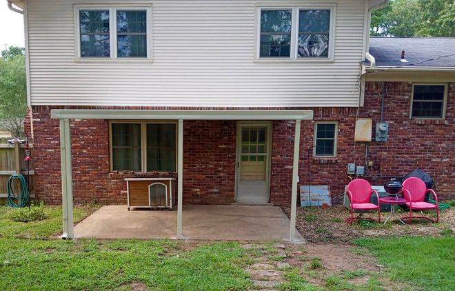 A brick house with a covered patio in front of it.