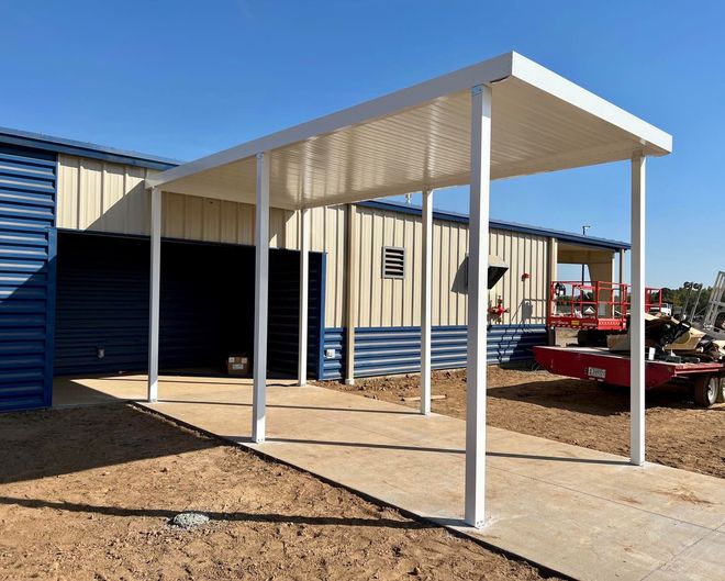 There is a covered walkway leading to a building under construction.