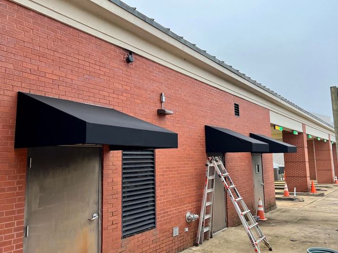 A brick building with a black awning on the side of it.