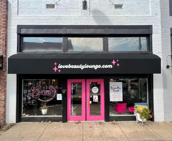 A store front with a pink door and a black awning that says lovebeautylounge.com