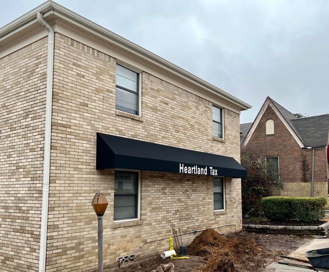 A brick building with a black awning on the side of it.