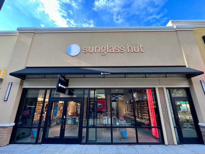 The front of a sunglass hut store with a blue sky in the background