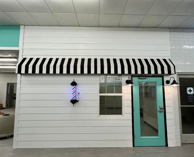 A barber shop with a black and white awning over the door
