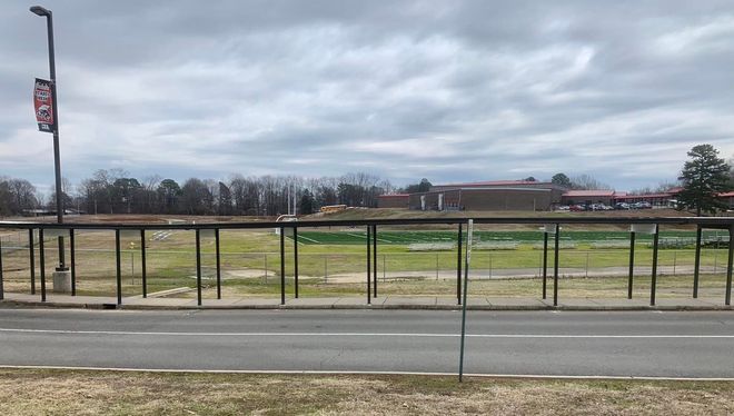 A fence surrounds a field next to a road.