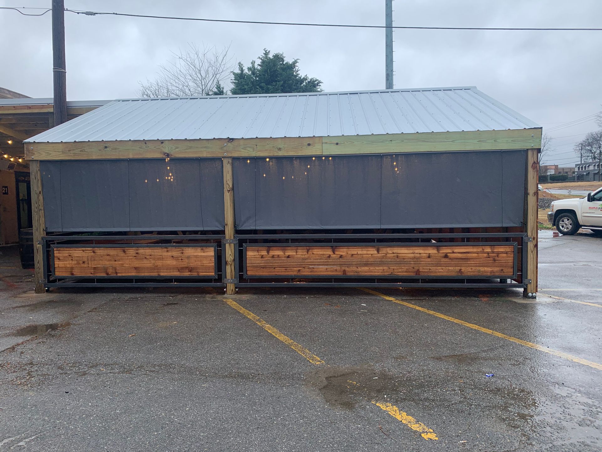 A car is parked in a parking lot next to a shed.