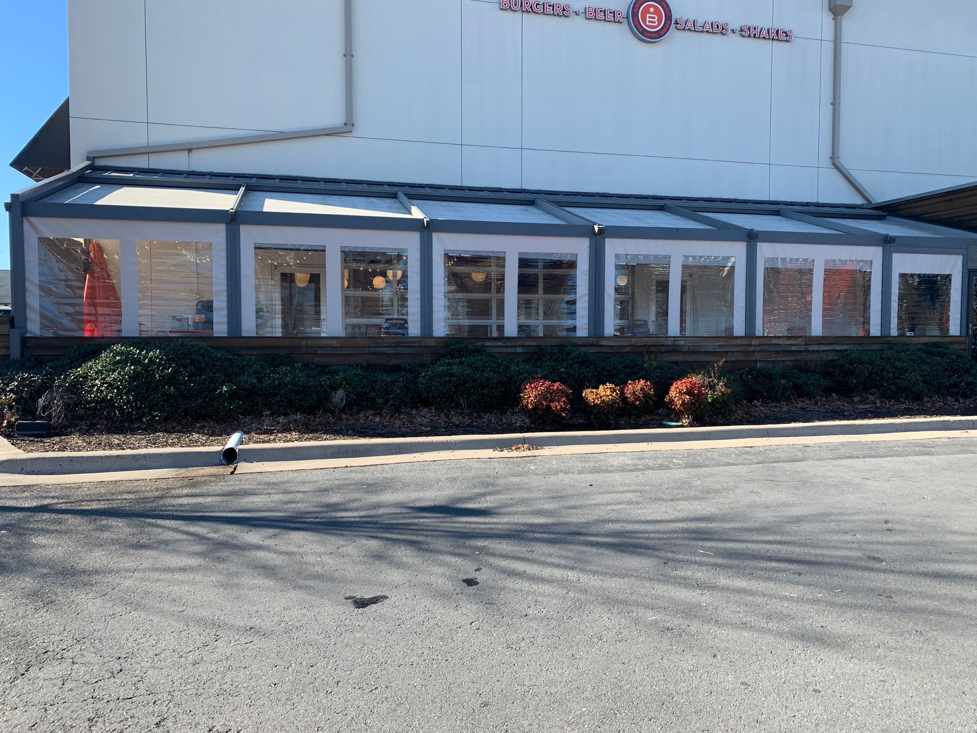 A large building with a lot of windows is sitting on the side of the road.
