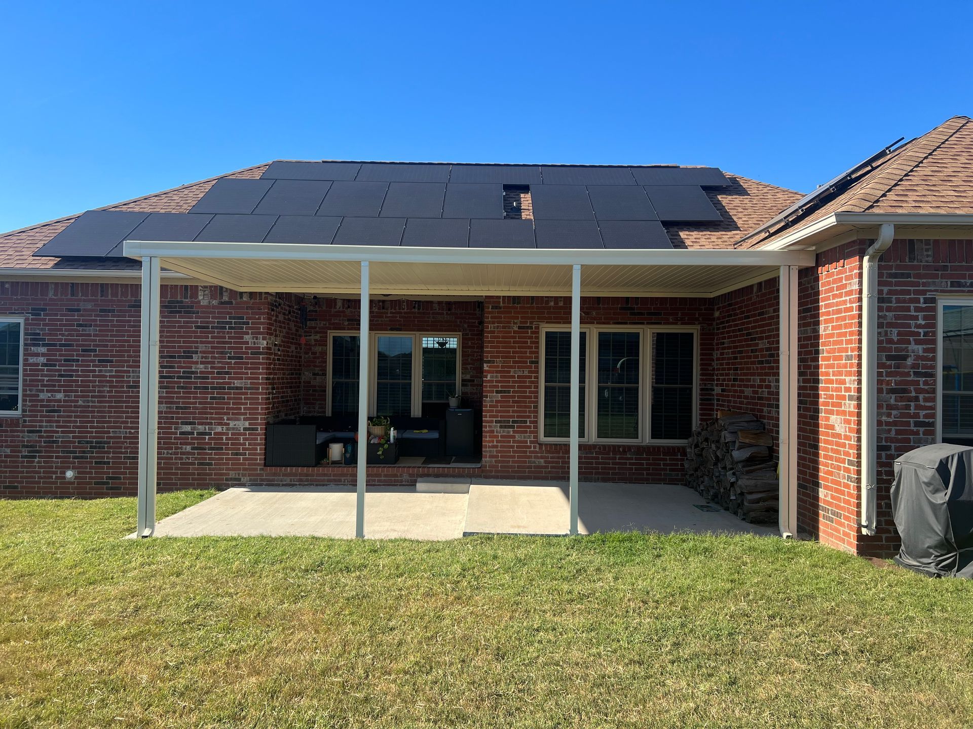 A brick house with a patio cover and solar panels on the roof.