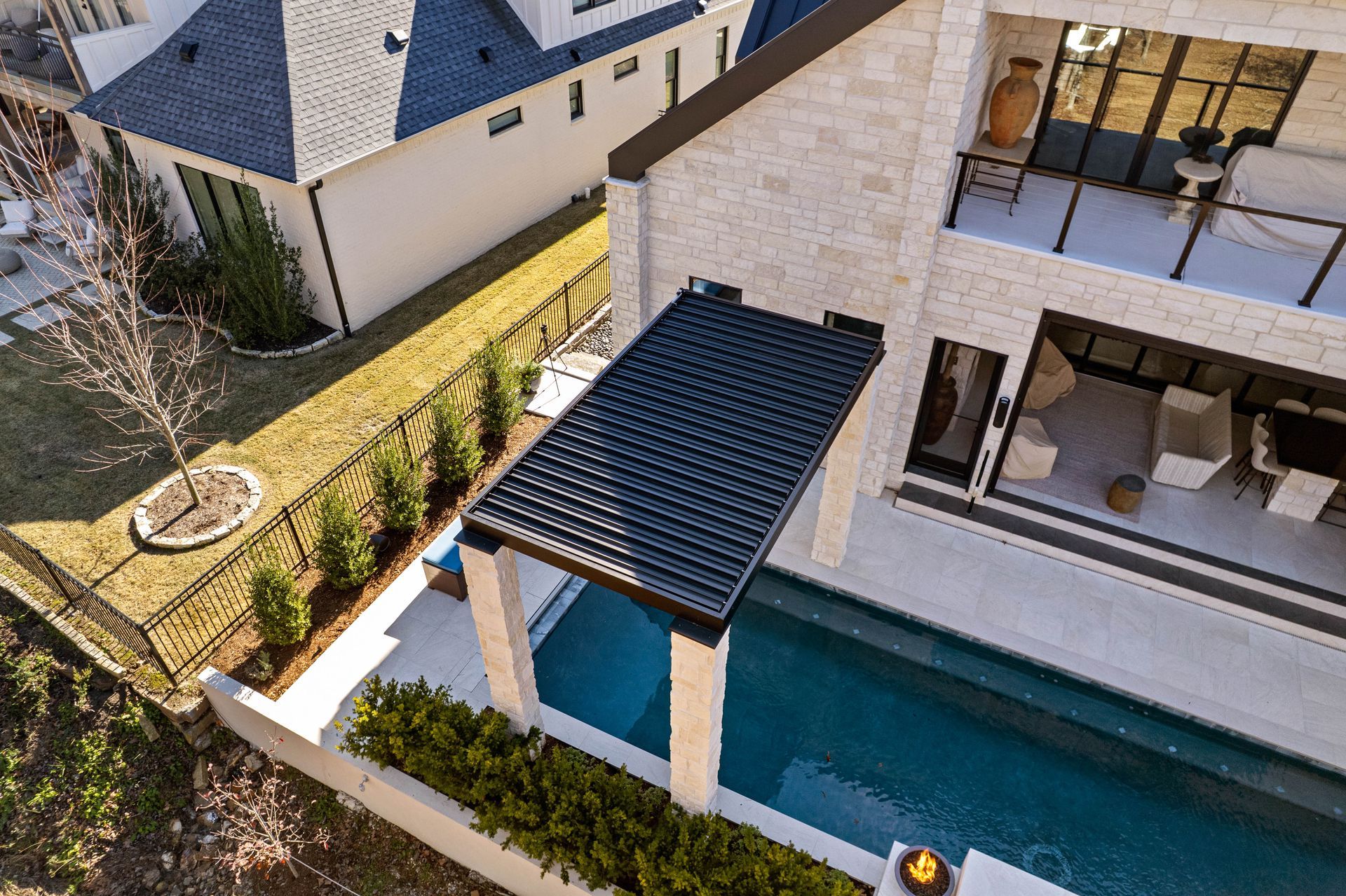 Aerial view of a modern house with a pool, covered patio, and landscaped backyard