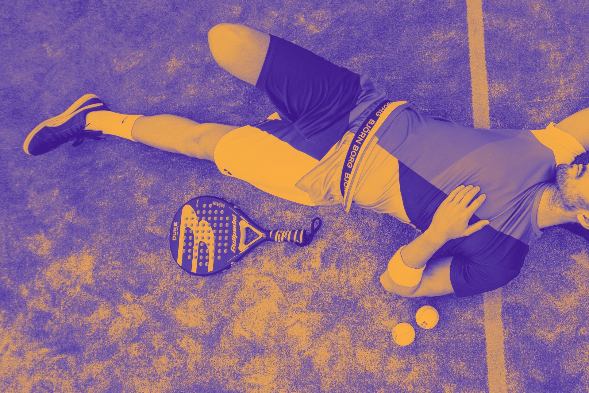 Een man ligt op zijn buik op een tennisbaan.