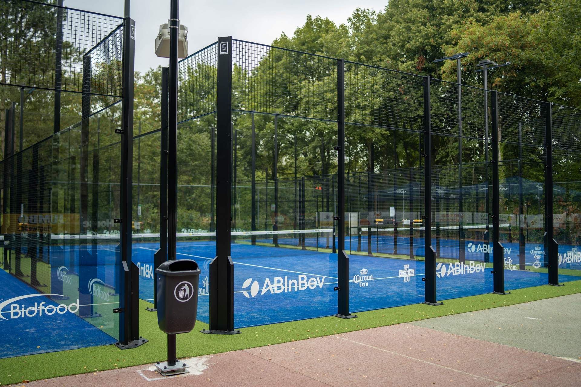 Een paddletennisracket ligt op een tennisbaan naast een tennisbal.