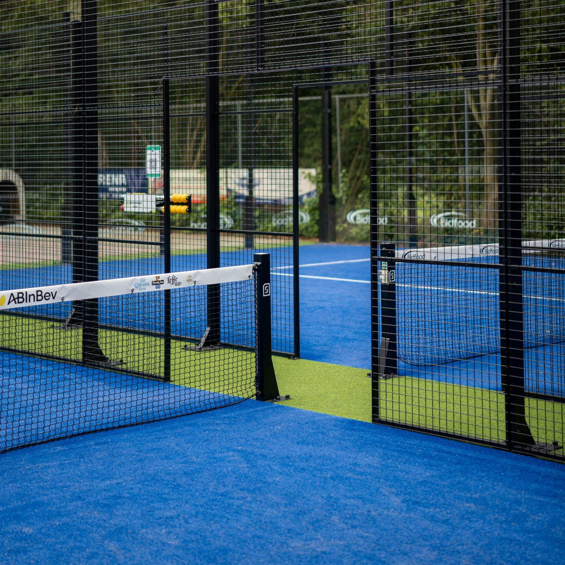 Een man en een vrouw houden tennisrackets en een wasmand vast op een tennisbaan.