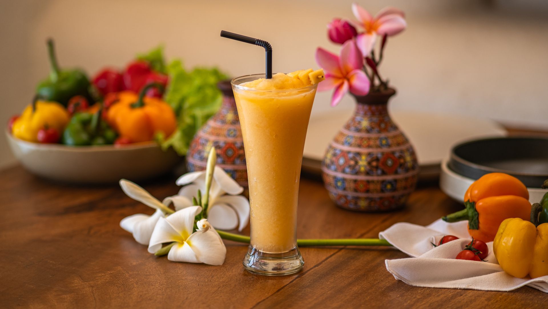 Two glasses of orange juice with lime garnishes on a round tray beside a swimming pool.