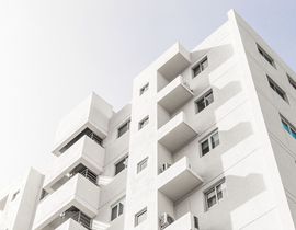 White apartment building viewed from below against a bright sky