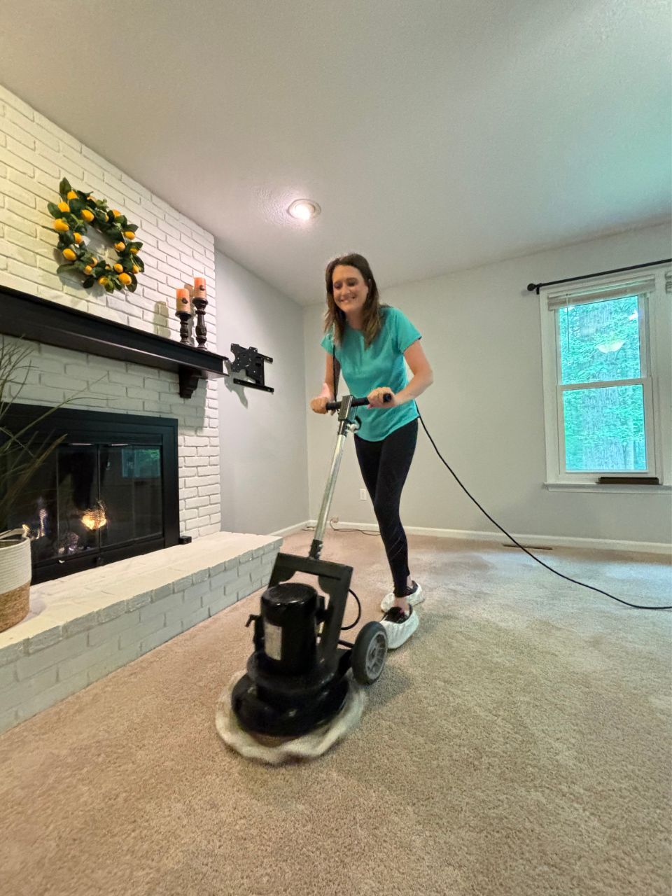A woman is using a machine to clean a carpet in a living room.