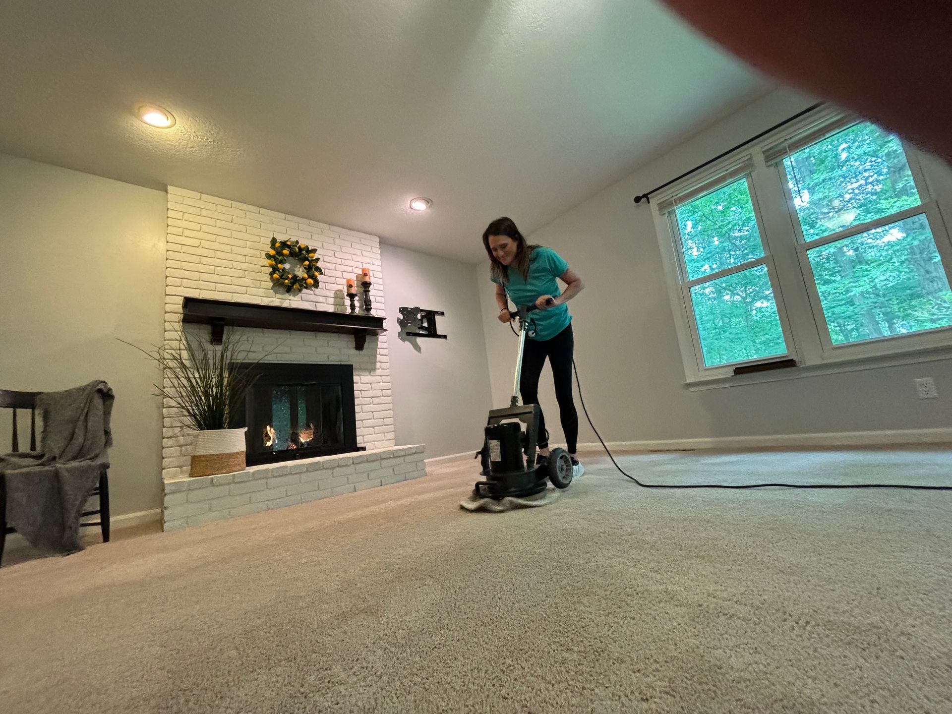 A woman is using a vacuum cleaner to clean a carpet in a living room.