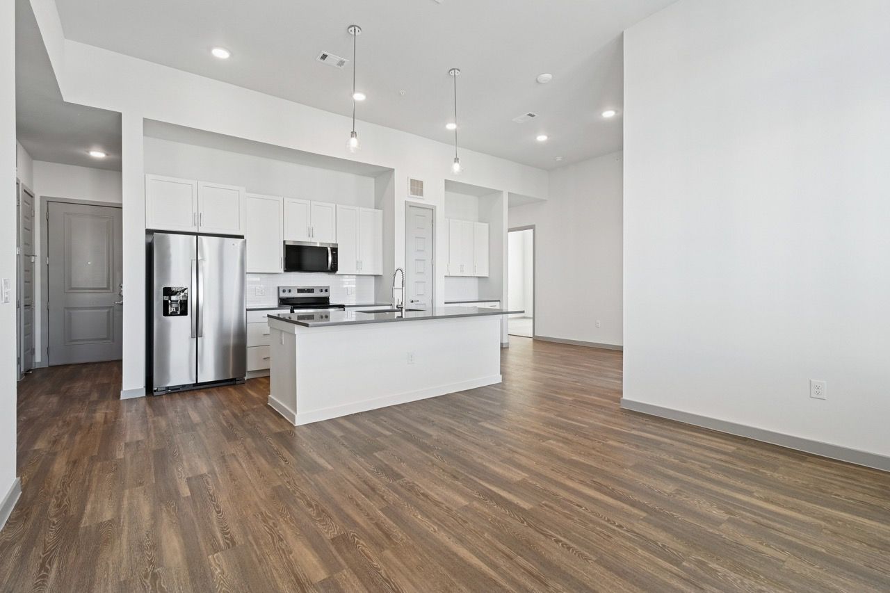Open-concept kitchen with white cabinets, stainless steel appliances, and island.